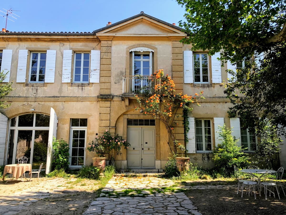 La façade de la maison sur la cour pavée, rosier en fleurs