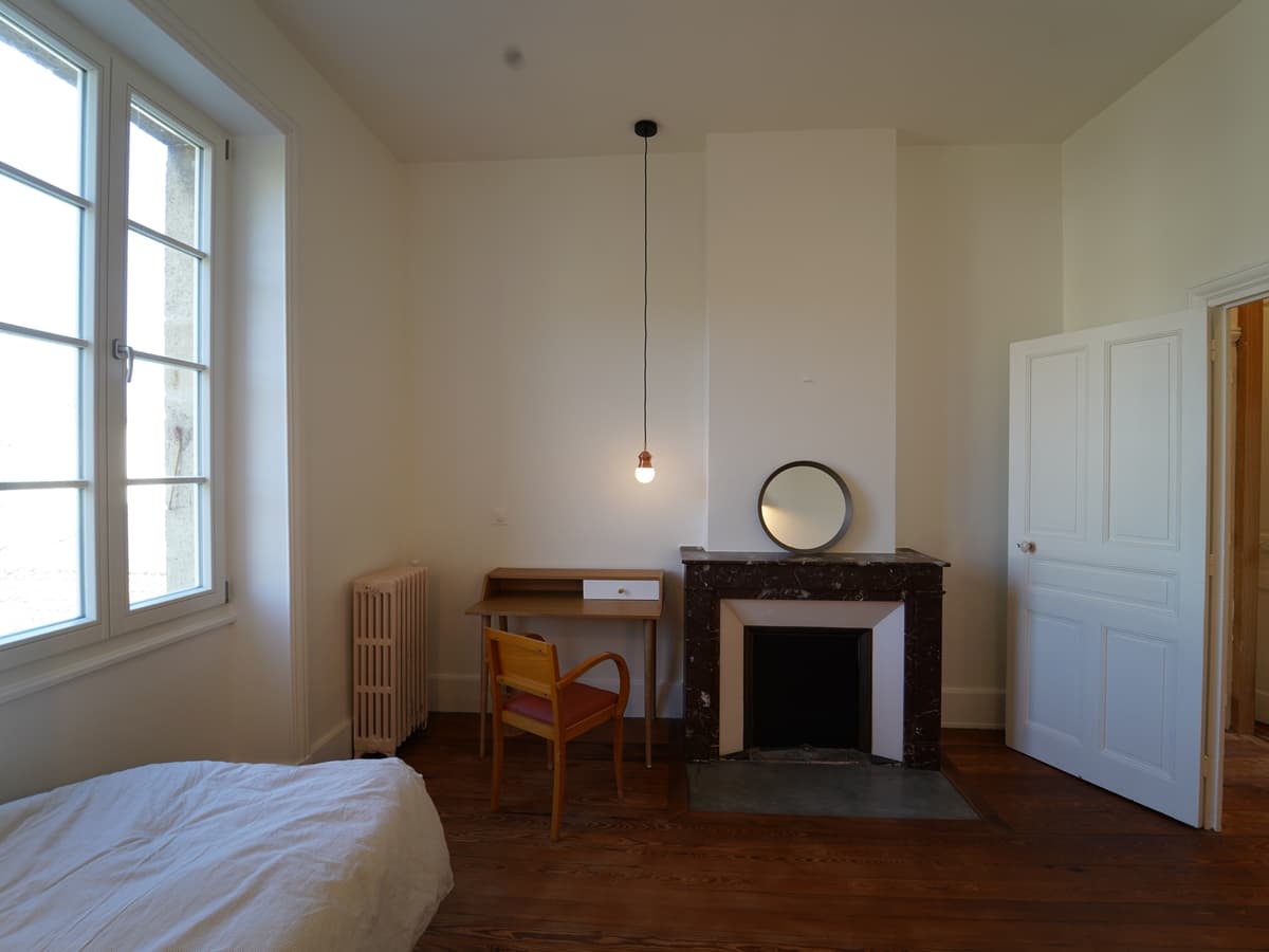 Une chambre claire, cheminée et haute fenêtre